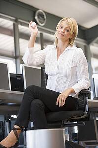 Businesswoman in office space throwing garbage in bin