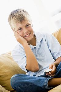 Young boy in living room with MP3 player smiling