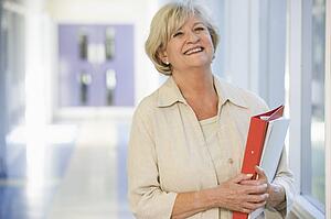 Woman standing in corridor with books (high key)