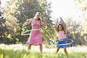 Woman and young girl with hula hoops outdoors smiling