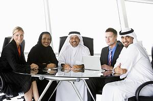 Five businesspeople in office with laptop smiling (high key/selective focus)