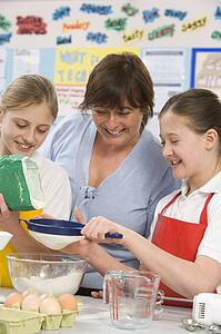 Students preparing ingredients in cooking class with teacher