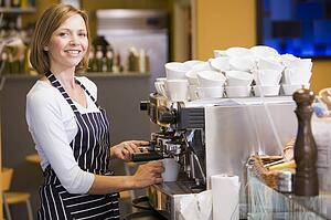 Woman making coffee in restaurant smiling