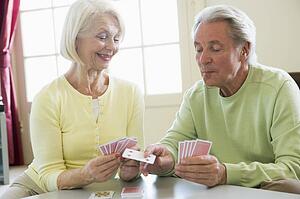 Couple playing cards in living room smiling