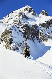 Snowboarder going up hill carrying board