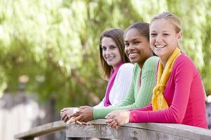 Teenage Girls Leaning On Wooden Railing