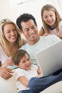 Family in living room with laptop smiling