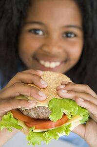 Young girl eating cheeseburger smiling