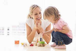 Mother and daughter indoors playing and smiling