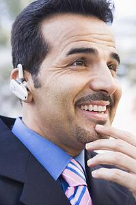 Businessman outdoors wearing headset and smiling (selective focus)
