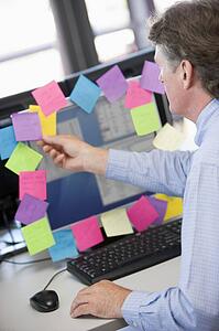 Businessman in office at monitor with notes on it