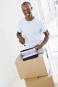 Man with roller and paint in new home smiling