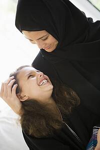 Mother and daughter in living room smiling (high key/selective focus)
