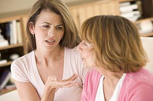 Two women sitting in living room arguing