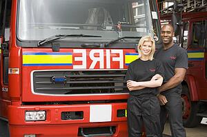 Two firefighters standing in front of fire engine