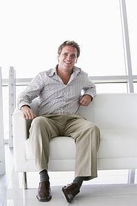 Businessman sitting in office lobby smiling