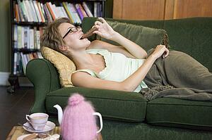 Young woman lying on sofa at home eating chocolate