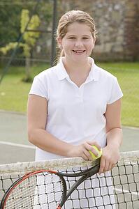 Young girl with racket on tennis court smiling