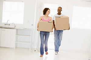 Couple with boxes moving into new home smiling