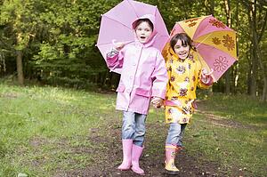 Two sisters outdoors with umbrellas smiling