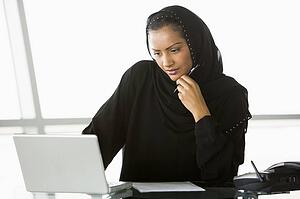 Businesswoman in office with laptop thinking (high key/selective focus)