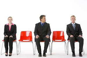 Three Business People Sitting On Red Plastic Seats 