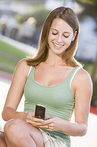 Teenage Girl Sitting Outdoors Using Mobile Phone