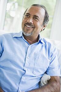 Man sitting in living room smiling (high key/selective focus)