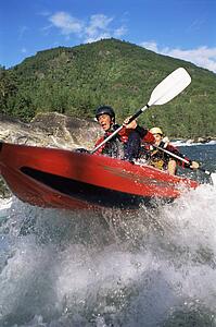 Two kayakers rowing in rapids (selective focus)