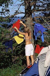 Woman outdoors at campsite hanging up wet clothes
