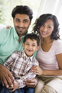 Family in living room sitting on sofa smiling (high key)