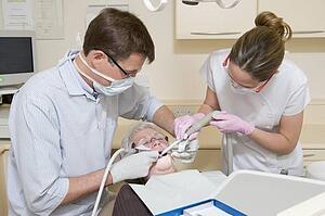 Dentist and assistant in exam room with woman in chair