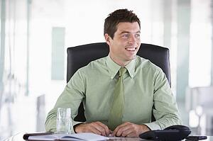 Businessman sitting in office with personal organizer smiling