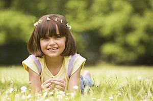 Young girl lying outdoors with flowers smiling