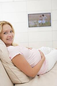 Pregnant woman watching television smiling