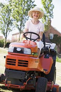 Woman outdoors driving lawnmower smiling
