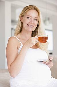 Pregnant woman with cup of tea smiling