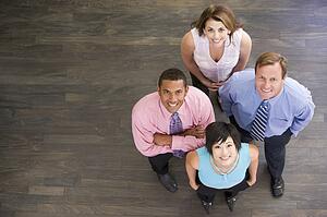 Four businesspeople standing indoors smiling