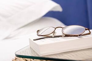 Empty bedroom with focus on eyeglasses and book