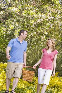 Couple walking outdoors with picnic basket smiling