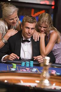 Three people in casino playing roulette smiling (selective focus)