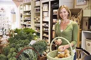 Woman in market looking at potatoes smiling