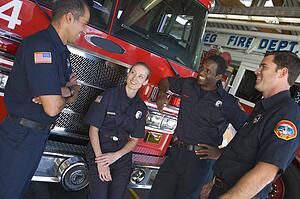 Four firefighters talking by fire engine