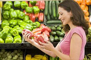 Woman shopping for bell peppers at a grocery store