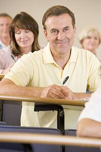 Man sitting in adult classroom with students in background (selective focus)