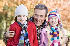 Grandfather and two children outdoors in park smiling (selective focus)