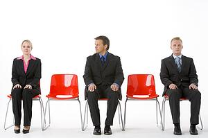 Three Business People Sitting On Red Plastic Seats 