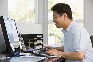 Man in home office using computer and smiling