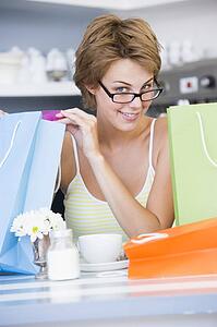 Young woman sitting at a table taking a break from shopping and drinking tea