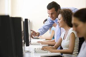 Man assisting woman in computer room